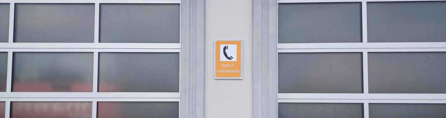 Feuerwehrtor mit Hinweisschild Notrufmeldestelle