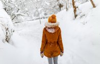 girl or woman walk in winter outdoor, snowy cold weather, countryside blizzard snowfall, yellow hat