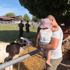 Mann mit Kleinkind auf dem Arm stehen vor Kalb