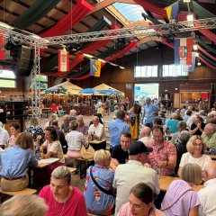 Blick in eine geschmückte Halle, in der viele Menschen sitzen
